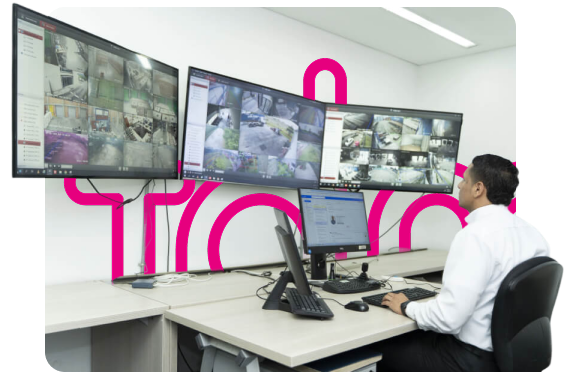 Persona vigilando numerosas pantallas de seguridad en una sala de control.