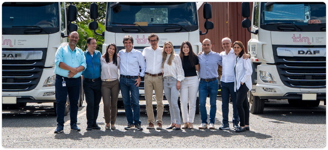 Grupo de personas sonriendo delante de dos camiones.